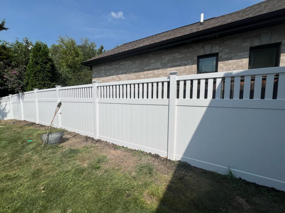 White vinyl fence with a decorative open top installed on a residential lot
