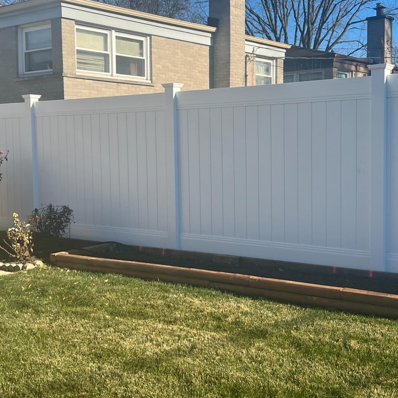 White vinyl privacy fence installed along a back yard