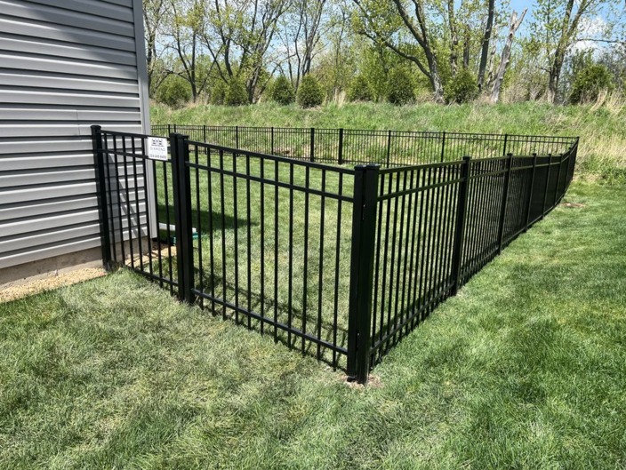 Black ornamental aluminum fence with a gate beside a building
