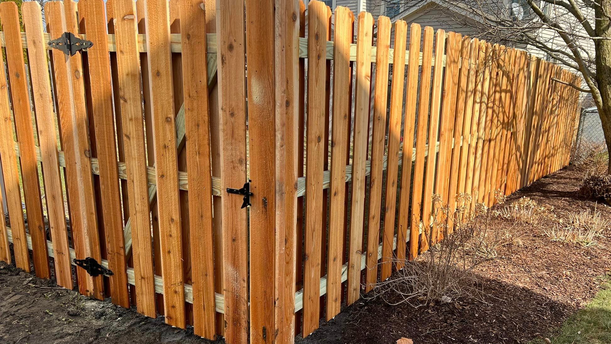 Cedar wood privacy fence run across a tree-lined property